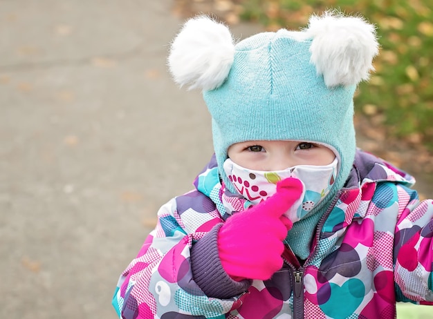 Klein meisje in winteroverall chirurgisch verband Coronavirus ziekte infectie quarantaine