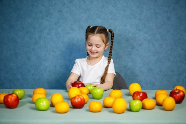 Klein meisje in wit t-shirt speelt en poseert met fruit