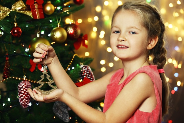 Klein meisje kerstboom versieren op lichte achtergrond