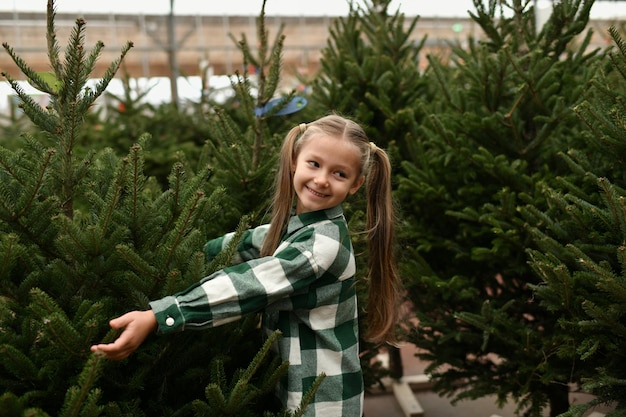 Klein meisje kiest een kerstboom op de markt