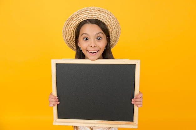 Klein meisje kind draagt zomer stijl hoed houd schoolbord informatie kopieer ruimte feestuitnodiging concept