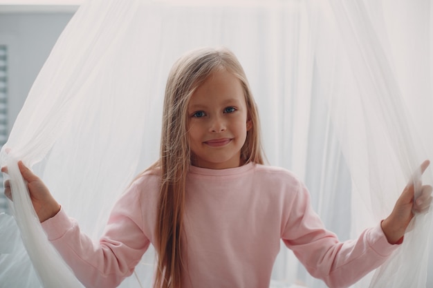 Klein meisje kind in roze kleren portret thuis.