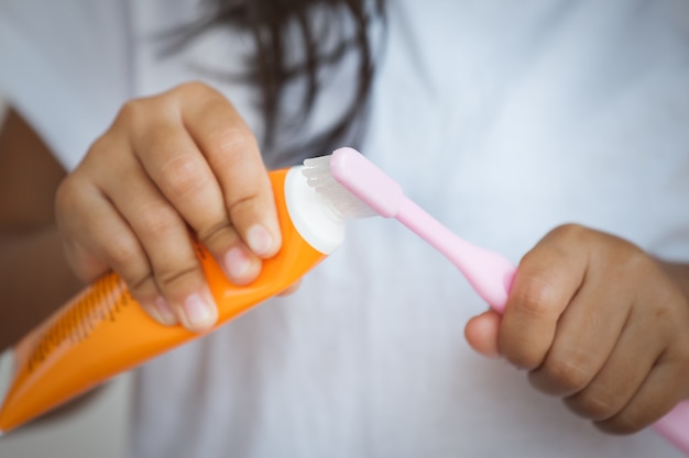 Klein meisje knijpt de tandpasta op de tandenborstel.