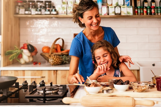 Klein meisje koken met haar moeder in de keuken. Baby chef-kok Concept.