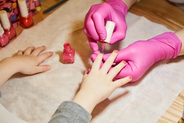 Klein meisje krijgt manicure in schoonheidssalon close-up