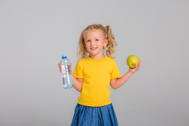 klein meisje lachend met een appel en een fles water