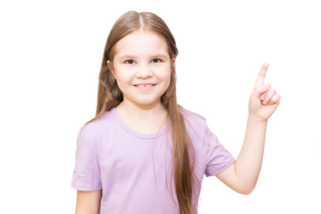 Klein meisje lacht en wijst met een vinger naar rechts geïsoleerd op een witte achtergrond
