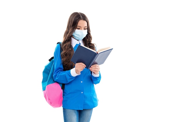 Klein meisje las een schoolboek met een beschermend gezichtsmasker om de overdracht van de ziekte van COVID-19 geïsoleerd op wit te voorkomen, kennis.