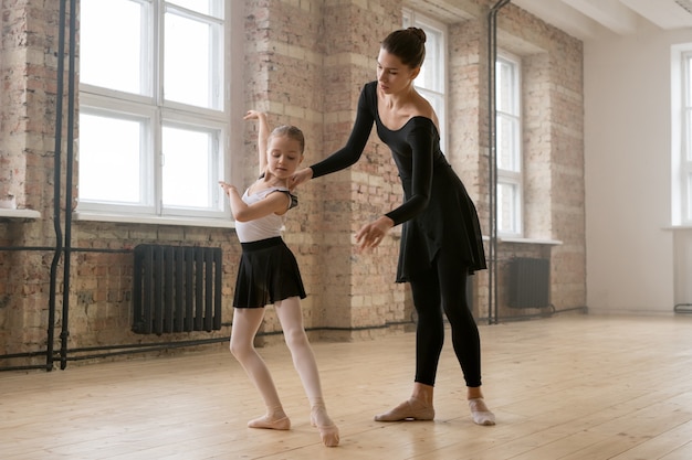Klein meisje leert in de juiste positie te staan tijdens haar balletlessen met trainer