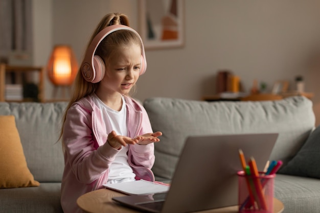 Klein meisje leert online met behulp van laptop videobellen thuis