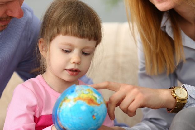 Klein meisje leren over navigatie en routes met globe in armen