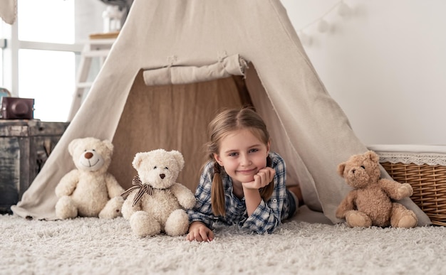 Klein meisje liggend in wigwam met knuffels