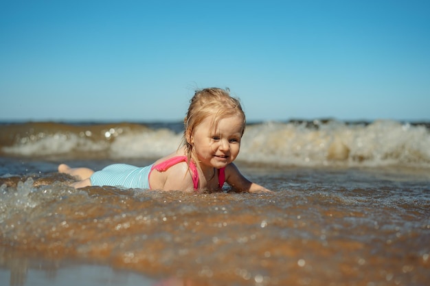 Klein meisje liggend in zee in golven