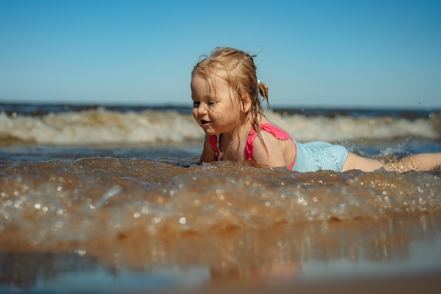 Klein meisje liggend in zee in golven