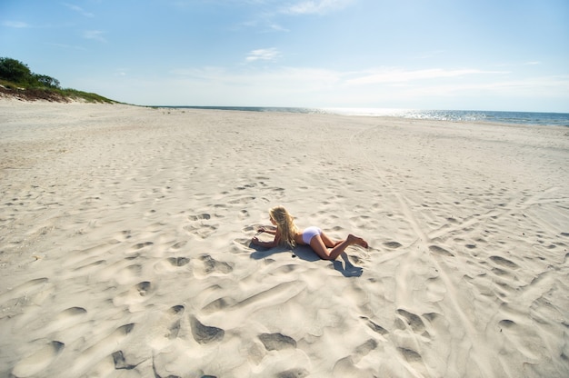 Klein meisje ligt op haar buik op het strand van de oostzee. curonian spit, litouwen,
