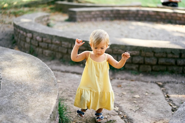 Klein meisje loopt in de buurt van een halfronde stenen steunmuur