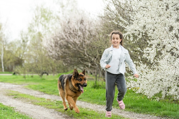 Klein meisje loopt met een hond in een bloementuin