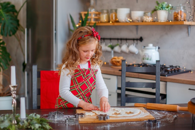 Klein meisje maakt koekjes voor Kerstmis in de keuken