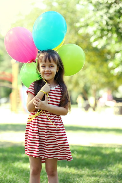 Klein meisje met ballonnen in het park