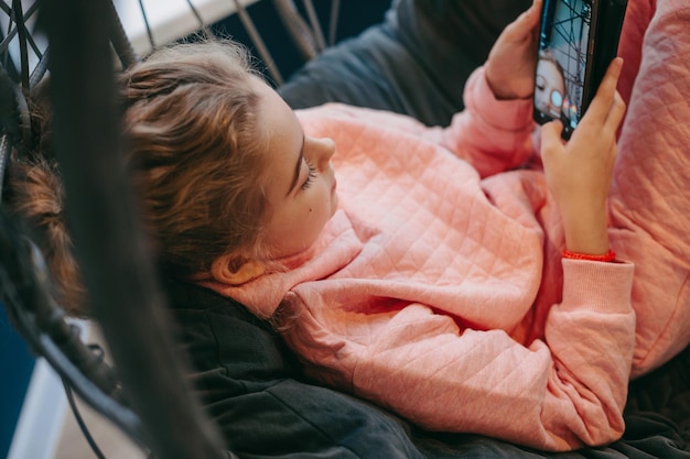 Klein meisje met behulp van mobiele telefoon thuis liggend op de bank mobiele computer technologie internet technologie bea