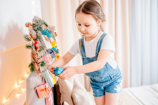 Klein meisje met de huidige doos handgemaakte adventskalender thuis. DIY kerst adventskalender voor kinderen