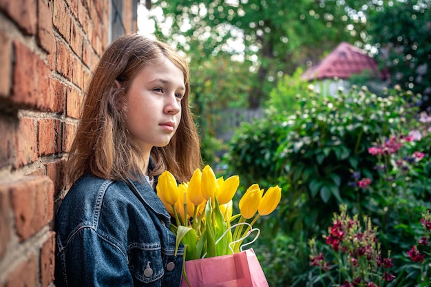 Klein meisje met een boeket gele tulpen