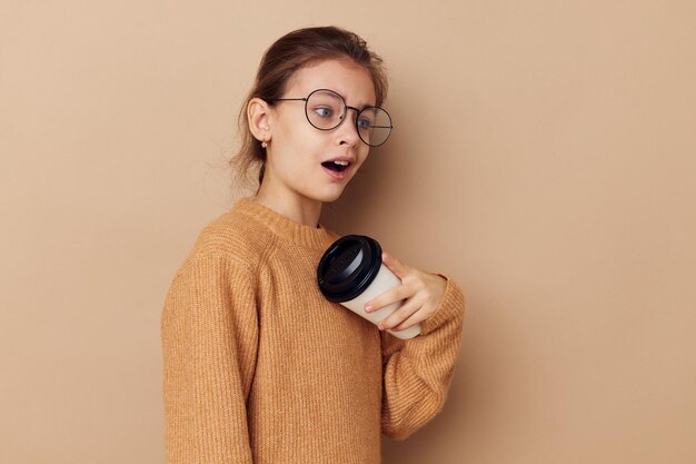 Klein meisje met een bril die glas met een drankje poseert