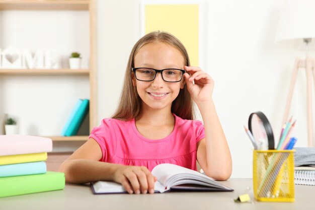 Klein meisje met een bril die thuis een boek leest