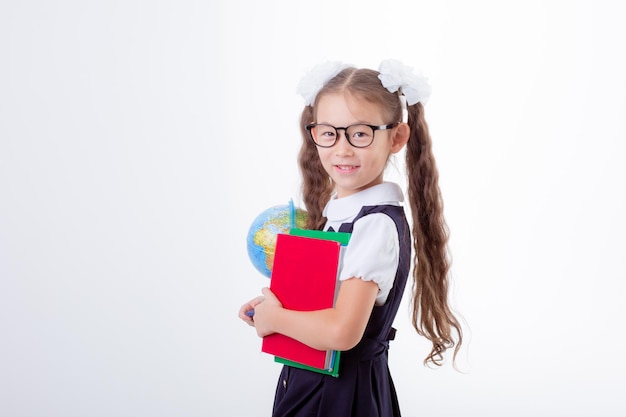 klein meisje met een bril en een schooluniform heeft een boek en een wereldbol geïsoleerd op een witte achtergrond