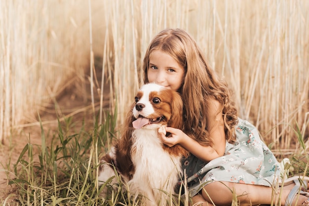 Klein meisje met een cavalier king charles spaniel hond die in de zomer in de natuur speelt