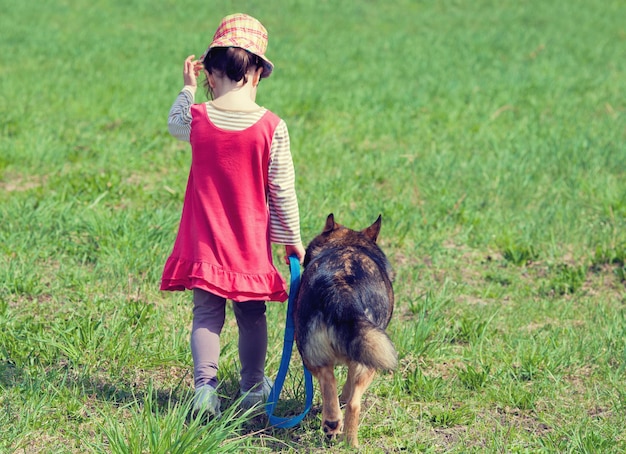 Klein meisje met een hond die op een groen gazon loopt