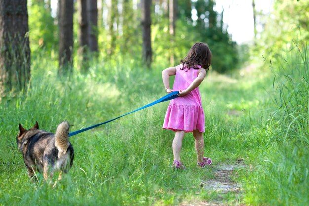 Klein meisje met een hond wandelen in het bos