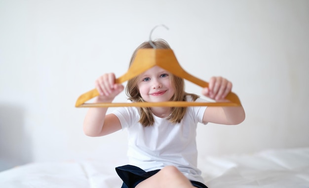 Klein meisje met een houten kledinghanger in haar handen