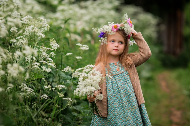 klein meisje met een krans van bloemen op haar hoofd voor een wandeling
