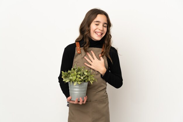 Klein meisje met een plant geïsoleerd op een witte achtergrond lacht veel