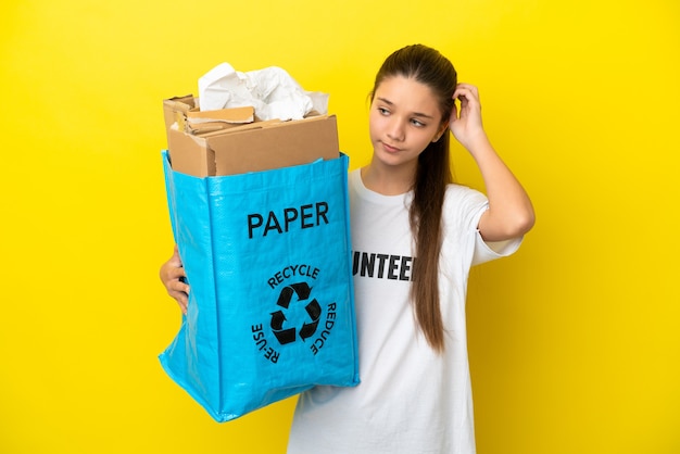 Klein meisje met een recyclingzak vol papier om te recyclen over geïsoleerde gele achtergrond met twijfels