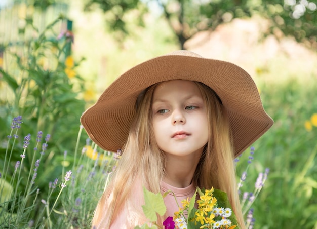 Klein meisje met een strohoed omringd door lavendelbloemen