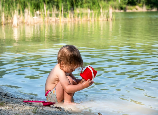 Klein meisje met emmer en schep spelen op het strand