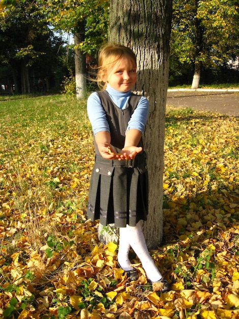 Klein meisje met geel blad in het park in de herfst