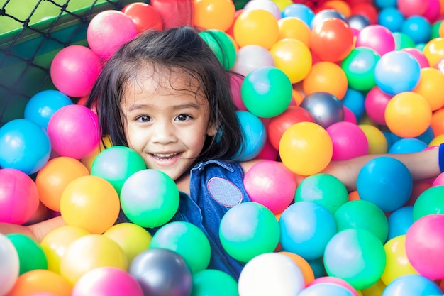 Foto klein meisje met gekleurde plastic ballen. grappig kind plezier binnenshuis.