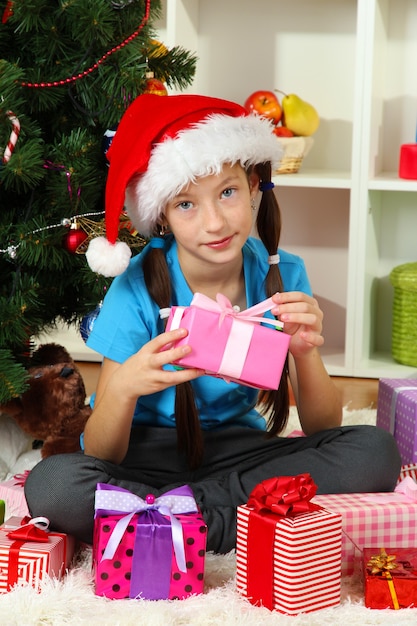 Klein meisje met geschenkdoos in de buurt van kerstboom