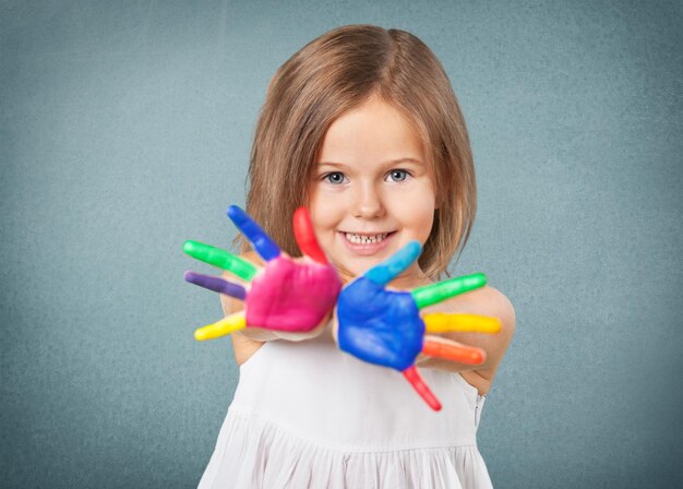 Klein meisje met geschilderde handen op een grijze achtergrond