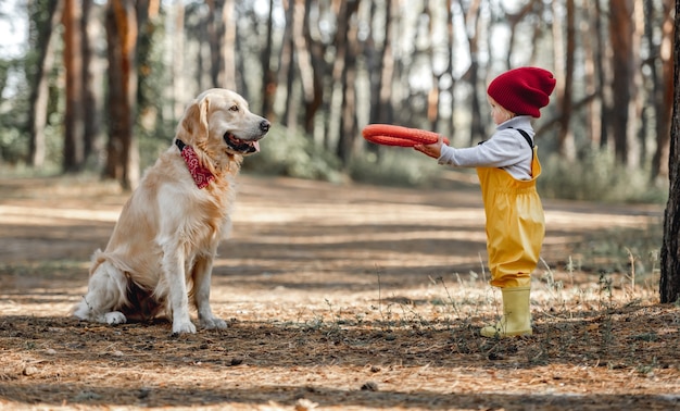 Klein meisje met golden retrieverhond in het bos