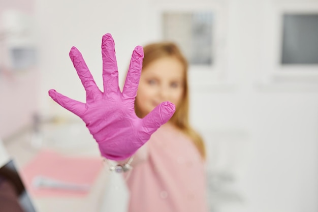 Klein meisje met handschoenen aan handen die zich in de stomatologiekliniek bevinden