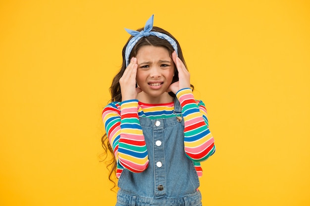 Klein meisje met hoofdpijn. retro meisje drukt geluk uit. zomervakantie vreugde. klein kind gele achtergrond. schoonheid en mode. gelukkige jeugd. ziek en gestrest voelen. moe meisje.