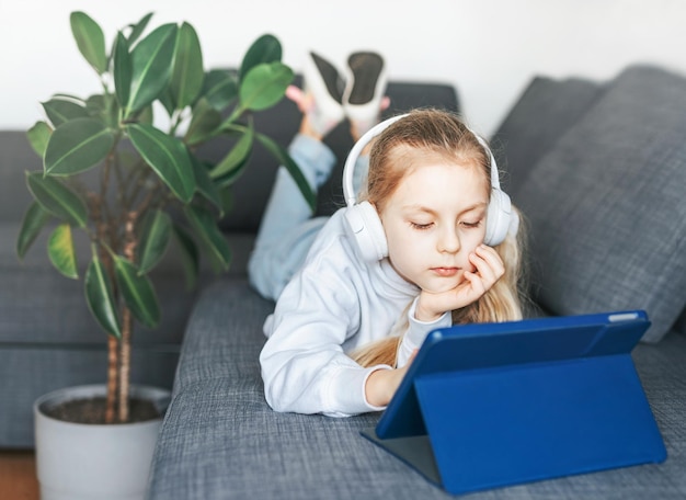 Klein meisje met koptelefoon en tablet thuis