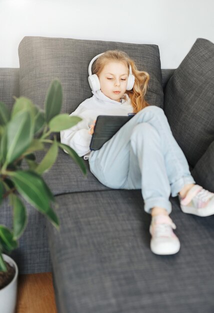 Klein meisje met koptelefoon en tablet thuis