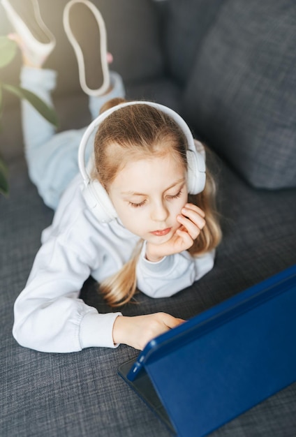 Klein meisje met koptelefoon en tablet thuis