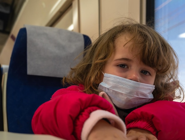 Foto klein meisje met masker verveeld in treinwagon