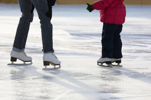 Klein meisje met moeder schaatsen op de ijsbaan